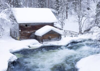 Huisje in sneeuwlandschap in Kuusamo aan rivier langzame sluitertijd