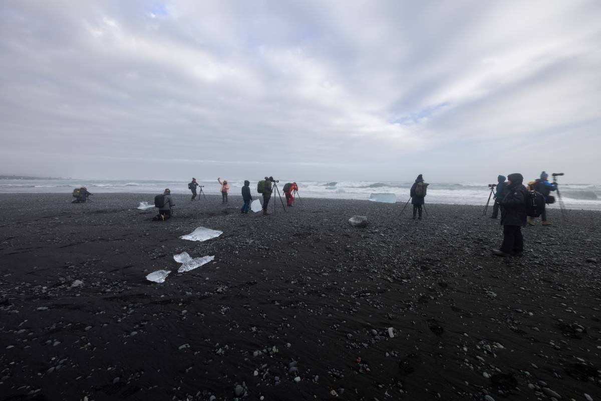 Fotografen op het zwarte strand met aangespoelde ijsschotsen